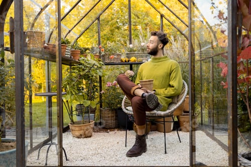 Preview: Man with flowerpot in greenhouse