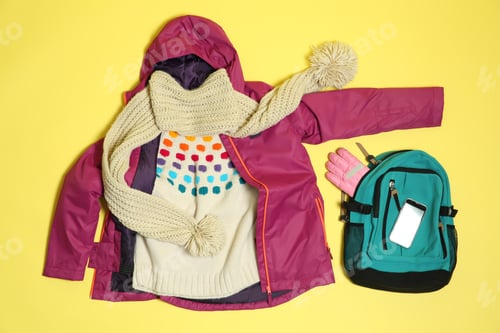 Preview: Flat lay composition with warm clothes for winter vacation on color background