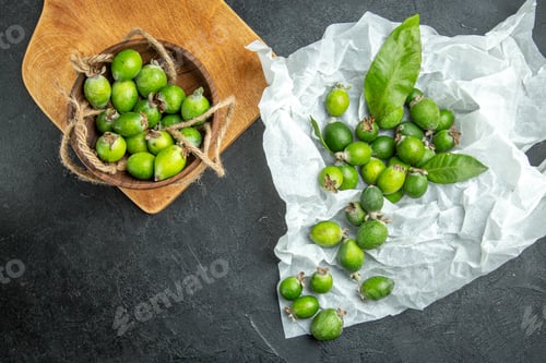 Preview: Natural fresh green feijoas in a small brown pot on wooden cutting board and white page on dark