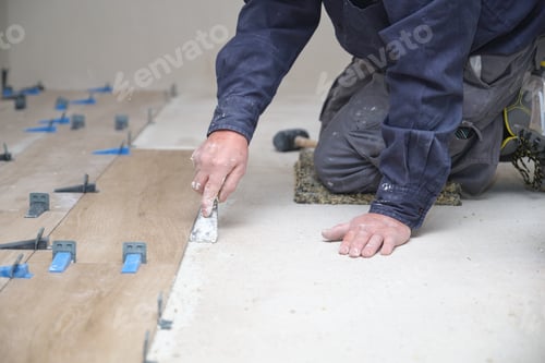 Preview: Unrecognizable senior mason laying ceramic wood effect tiles.