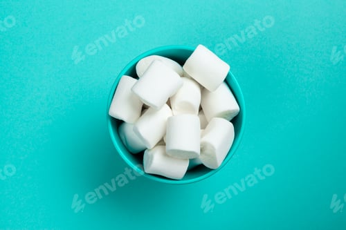 Preview: marshmallow laid out on blue paper background. pastel creative textured pattern