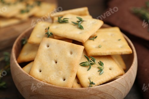Preview: Tasty salty crackers with thyme on wooden table, closeup
