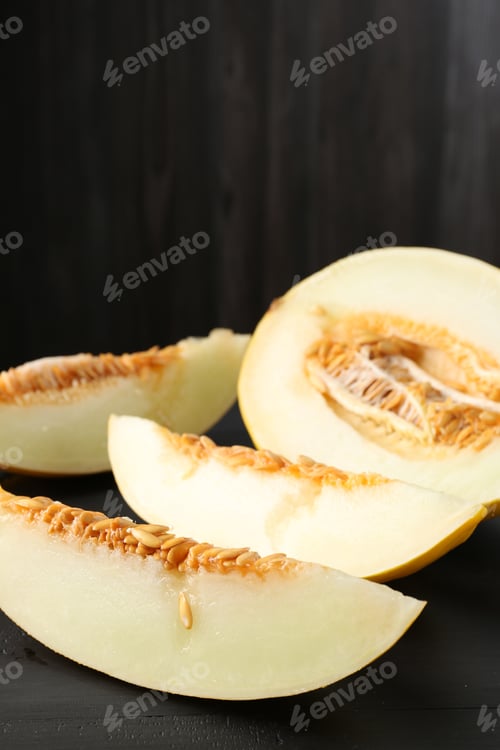 Preview: Cut ripe melon on black wooden table, closeup
