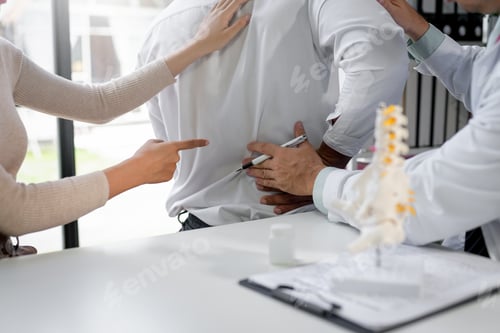 Preview: Doctor pointing with pen at patient back describing pain in hospital