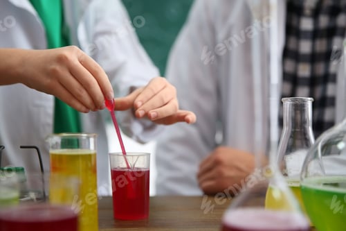 Preview: Teacher with pupil making experiment at table in chemistry class, focus on hand