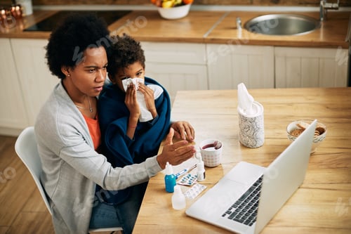 Preview: Worried African American mother and her ill son having video call over laptop from home.