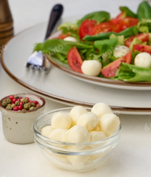 Preview: Mozzarella balls in glass bowl and salad on a white background