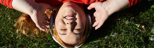 Preview: Joyful plus-size woman enjoying music while exercising in a vibrant park