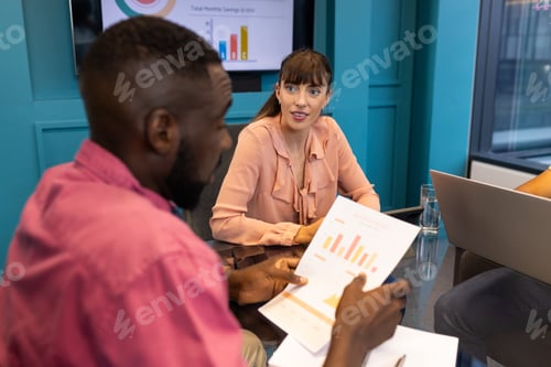 Preview: Discussing financial charts, colleagues collaborating in modern office meeting room