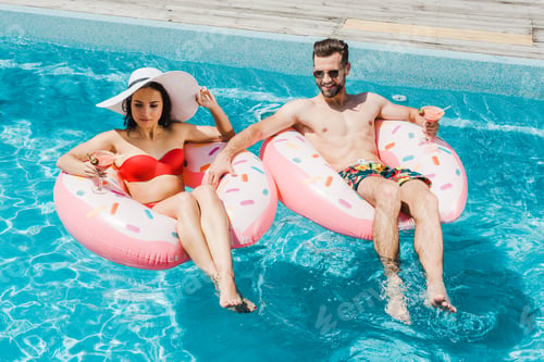 Preview: girl in swimsuit and straw hat near handsome man holding cocktail glass