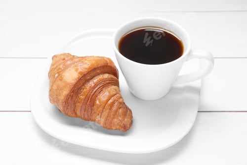 Preview: Tasty breakfast. Cup of coffee and croissant on white wooden table