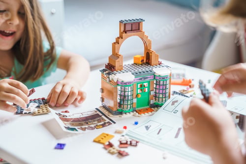 Preview: Girls, sisters play kids constructor, build house Lego Harry Potter from bricks, blocks by assembly