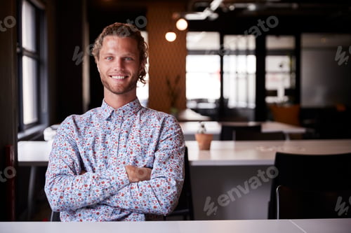 Preview: Millennial white male creative sitting in an office with arms crossed smiling to camera, close up