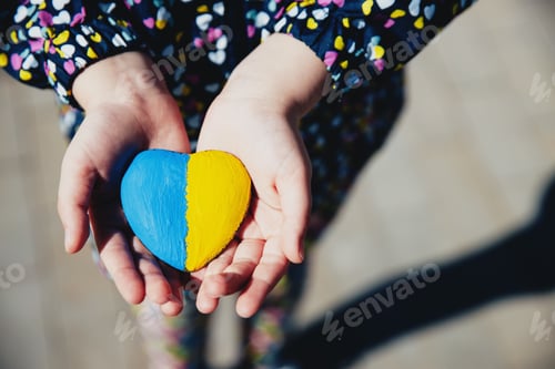 Preview: Small little kid hold heart shaped stone with Ukraine national flag or anthem