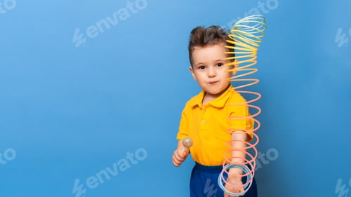 Preview: A boy with a lollipop stands on a blue background of a wall with a toy. Copy space