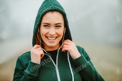 Preview: Smiling young girl with green hoodie is posing in front of camera during workout.