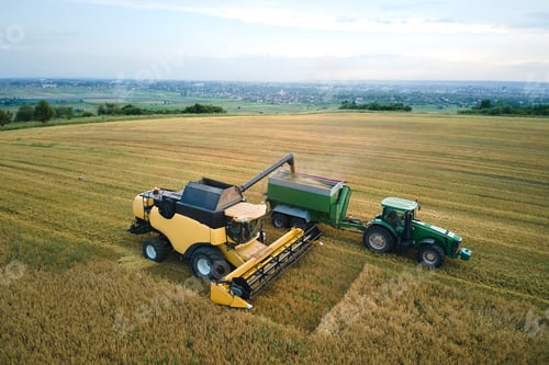 Preview: Aerial view of combine harvester unloading grain in cargo trailer working during harvesting season