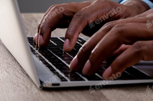 Preview: Close up of businessman using laptop on wooden surface against grey background