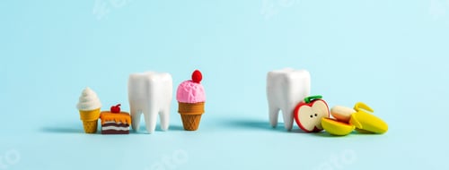 Preview: Human tooth model and set of sweet food on blue background. Wide banner.