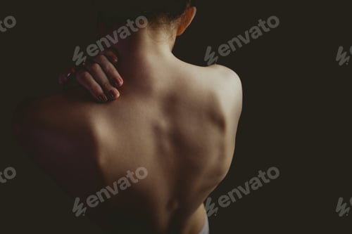 Preview: Nude woman with a shoulder injury on black background