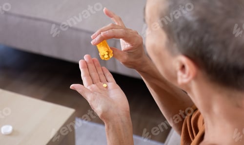 Preview: Elderly Woman Holding Medicine Bottle and Pills in Hand, Healthcare and Medication Concept