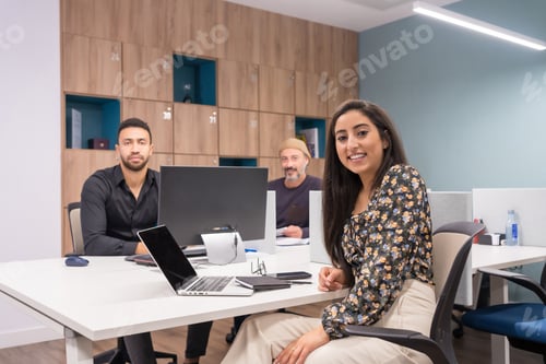 Preview: Portrait of three colleagues sitting on a co-working desk