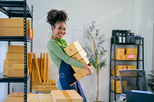 Preview: Smiling african american female business owner carrying packages in her store