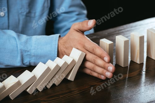 Preview: close up view of man sitting at desk and preventing wooden blocks from falling