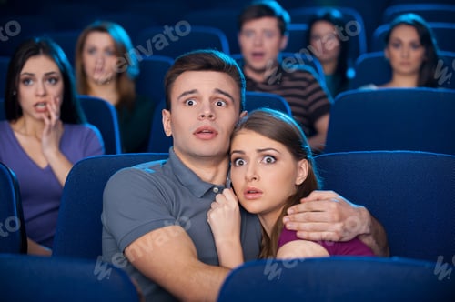 Preview: Watching horror movie. Shocked young couple bonding to each other while watching movie at the cinema