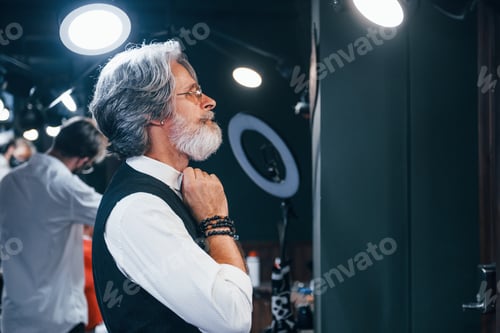 Preview: Stylish Senior Man Adjusting Collar in Barber Shop