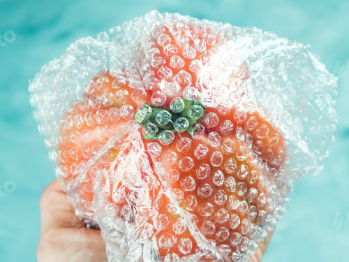 Preview: Tomato in plastic package on turquoise