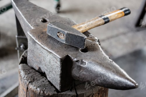 Preview: A closeup shot of a hammer resting on an anvil.