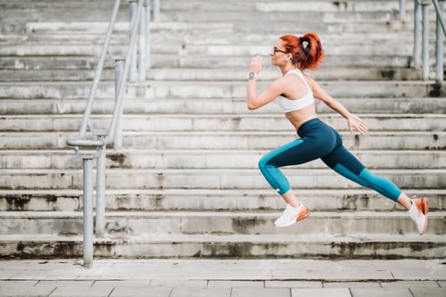 Preview: Portrait of sportswoman with fit body jumping and running on stairs background