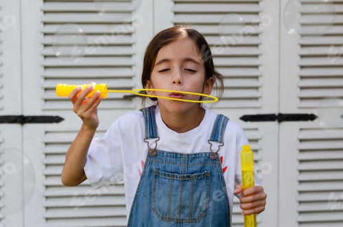 Preview: A little girl making bubbles outdoors.