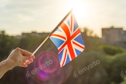 Preview: Hand holding Great Britainin flag an open window.