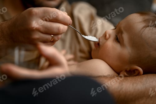 Preview: Dad keeps his little son in his arms and feeds him porridge