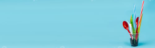 Preview: disposable cutlery and ground in plastic cup on blue background, panoramic shot