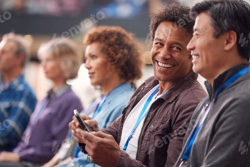 Preview: Businessman In Presentation At Conference Checking Mobile Phone