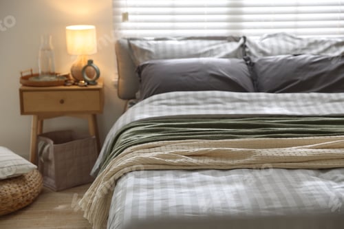Preview: Comfortable bed with soft linens and blankets in room, closeup. Home textile