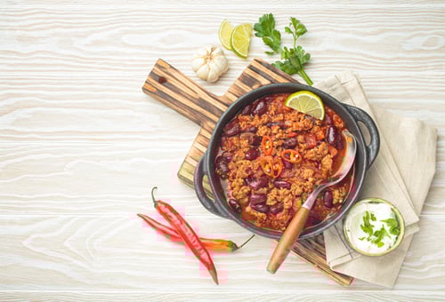 Preview: Mexican dish chili con carne with minced meat, red beans, lime, and spices top view, space for text