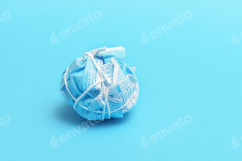Preview: The concept of ending a pandemic. Crumpled medical mask on blue background.