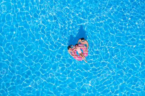 Preview: Happy family with inflatable ring in swimming pool, top view. Summer vacation