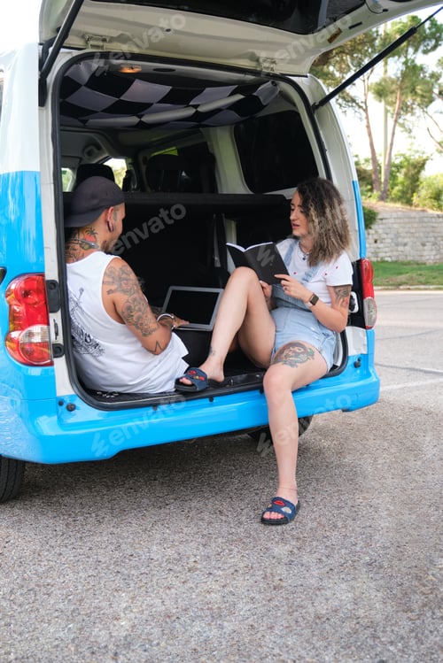 Preview: Young tattooed couple reading and working in the back of the van.