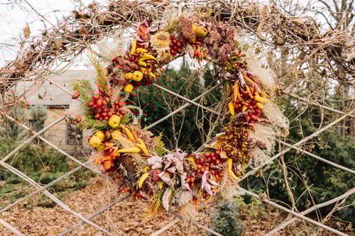 Preview: Autumn decorative wreath of fruits, spikelets and berries hangs on a mesh fence