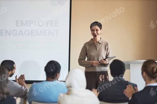 Preview: Happy experienced coach with tablet looking at audience with smile