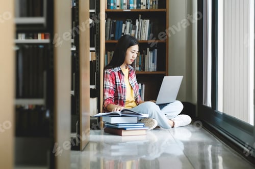 Preview: Young university student using laptop for online learning, searching and learning at library.