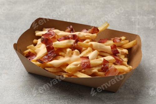 Preview: Tasty potato fries, cheese sauce and bacon in paper container on grey table, closeup