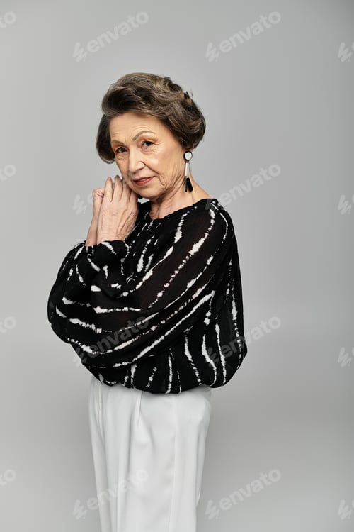 Preview: A beautiful woman in her 60s elegantly poses in sophisticated attire, exuding timeless fashion.