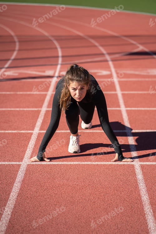 Preview: Confident fit woman sprinter on treadmill rubber stadium or running track getting ready to start run
