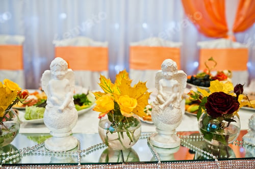 Preview: Yellow autumn leaves in vases with plaster angels at the wedding table newlyweds